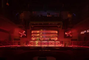 A bar area with a row of liquor bottles, chairs, and red accents on the walls