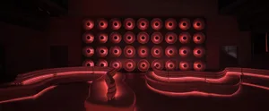 A modern living space with a large white leather couch in front of a wall covered in red lights, creating a warm and inviting atmosphere