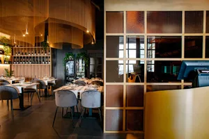 Elegant dining space with wooden tables, chairs, and wine glasses, set in a sophisticated and inviting atmosphere