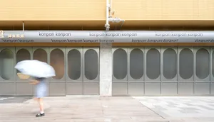 A commercial building with two large glass doors, one on either side, with the word Konpan written in white letters, made of concrete