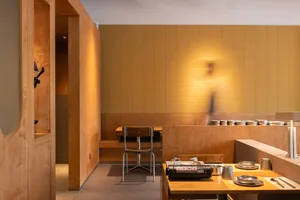 Warm and inviting restaurant interior with wooden walls and floors, featuring chairs and dining tables with a bowl on one table
