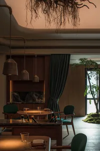 A warm and inviting living space with a dining table, fireplace, and potted plant, featuring wooden elements and well-lit with multiple bottles on the table
