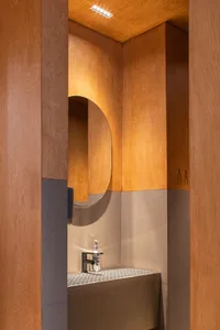Bathroom with a metal sink under a wooden-framed mirror, giving off an industrial vibe in a well-lit space