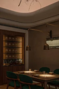 Warm and inviting dining space with a wooden table, chairs, and wine glasses, set up for a social gathering