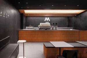 Industrial kitchen with a counter featuring two coffee machines and cups, clean and well-organized atmosphere