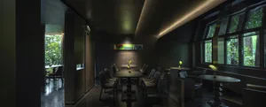 A dimly lit restaurant with a long dining table and chairs, surrounded by a dark and mysterious atmosphere