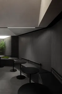 A dark empty room with three dining tables and four chairs, creating a sense of mystery