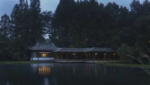 Asian-style building near a body of water with a distinctive roof design, natural light entering through windows, and a serene atmosphere