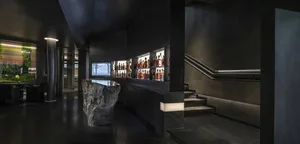 A sophisticated bar with a black and white theme, featuring stone and concrete elements, and bottles on shelves