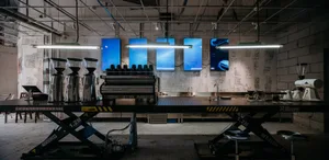 Industrial kitchen with a large coffee machine, TV screens, and various appliances for efficient food preparation and service