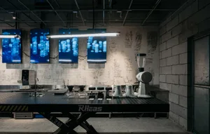 Industrial kitchen dining space with a concrete floor, a dining table, chairs, and decorative vases and bowls
