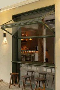 A cozy bar area with chairs and a dining table, surrounded by bottles and an inviting atmosphere