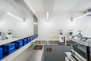 Well-lit modern kitchen with stainless steel countertops, sink, and appliances