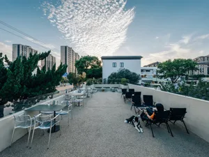 A sunny outdoor patio with wicker chairs and tables, surrounded by sunlight and a relaxed atmosphere