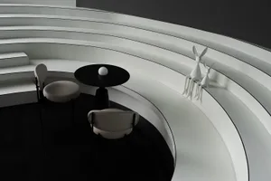 Modern living space with white walls, black floors, and a circular design featuring chairs, a dining table, and deer statues