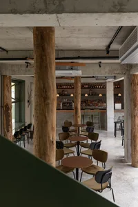 A spacious bar area with wooden columns, dining tables, and a well-stocked bar, perfect for socializing and enjoying drinks