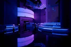 Purple-walled space with chairs and dining tables, providing a modern and social atmosphere