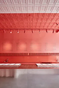 A modern restaurant interior with a red accent wall, counters, and signs, creating a warm and inviting atmosphere