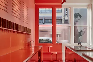 Warm kitchen with red walls, natural light, and a chair for dining or additional seating