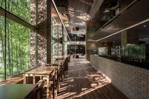 Open restaurant interior with wooden floors, brick walls, and dining tables and chairs