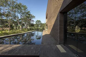 A serene outdoor space with a brick building, empty pool, and surrounding trees