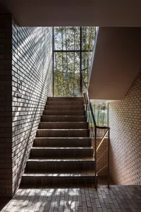 A rustic staircase with brick steps and a window on one side, surrounded by a sense of depth and dimension within a building