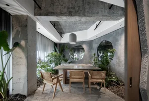 Cozy dining area with a wooden table, stone accents, and potted plants, creating a modern and inviting atmosphere