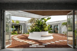 A well-designed indoor space with a large circular planter surrounded by multiple potted plants and lush greenery