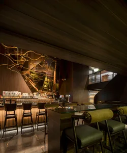 A bar area with a wooden counter and stools, surrounded by bottles and creating a welcoming atmosphere for socializing and relaxation
