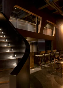 Elegant interior design with a spiral wooden staircase, black railing, and wooden floor, featuring seating areas and a dining table