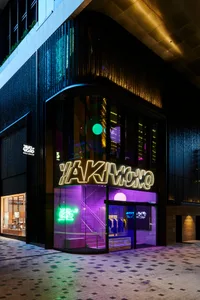 夜晚熱鬧的城市街道，伴有一棟大型建築物上的紫色霓虹燈招牌，周圍環繞其他招牌與明亮燈光