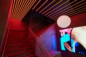 A stone staircase in a museum or art gallery with a large screen and neon lights creating a modern and contemporary atmosphere