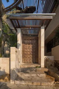A traditional entrance with a wooden doorframe, stone walls, and a rustic atmosphere, leading to a courtyard area
