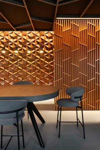 A modern dining space with a large wooden table and chairs, surrounded by natural materials and warm lighting