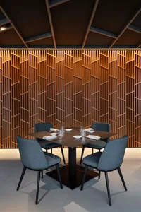 Cozy dining space with a wooden table and grey chairs, surrounded by cups and a warm atmosphere