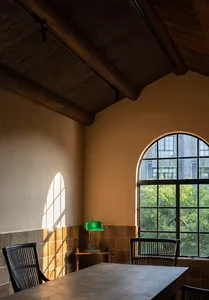 Cozy room with a wooden ceiling, stone wall, two chairs, a dining table, and a clock on the wall