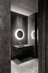 Modern bathroom with a sink, mirror, and shower area, featuring black marble flooring and sleek design