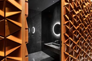 Modern bathroom with a sink, mirror, and shower area, featuring black tiles and a sleek design