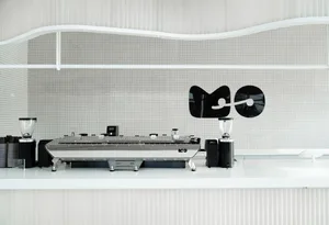 Industrial kitchen with modern appliances, white walls, and tiled floors, featuring two sinks and a minimalist design