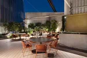 A relaxed outdoor dining area with tables, chairs, and umbrellas, perfect for a night meal