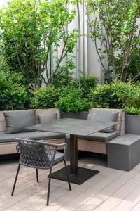 A wooden dining table with a metal base is surrounded by three chairs in a comfortable outdoor seating arrangement