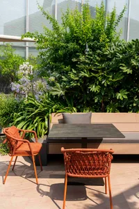 A wooden deck with a bench and chairs, two dining tables, and a comfortable outdoor seating arrangement for socializing or meals