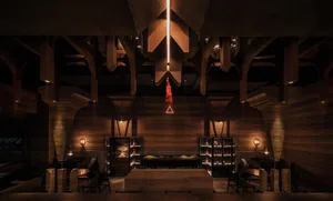 A warm and inviting dining space with wooden walls and ceiling, featuring a dining table and chairs, and decorative bottles