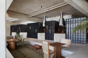 Modern restaurant interior with dining area, kitchen, and potted plants, featuring sleek design and functionality