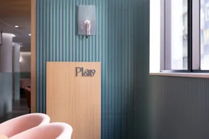 Bathroom with a pink bathtub, wooden stand, and green tile walls, featuring a clean and organized atmosphere