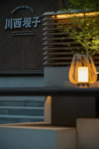 A modern Asian restaurant with a dining area, tables, chairs, and potted plants, featuring textured walls and a warm atmosphere