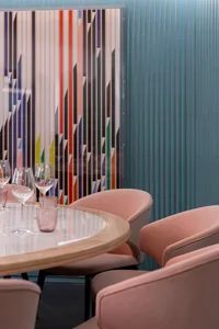 Dining table with pink chairs, wooden table, and wine glasses, set in a modern and stylish room with pink accents