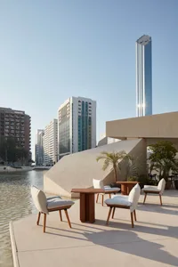 A city building's patio area with chairs and dining tables arranged around a water feature, creating a comfortable atmosphere for gathering and enjoying the view