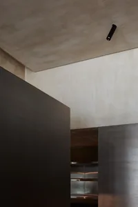 A spacious commercial space with a high ceiling, featuring a concrete wall and a textured wall, giving a modern and contemporary atmosphere