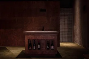 A darkened room with a wooden counter featuring several wine bottles, creating a cozy and intimate atmosphere for socializing